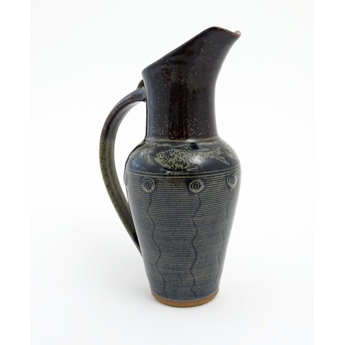 93 - A studio pottery jug by Jennie Gilbert with banded fish detail to shoulder and relief roundel decora... 