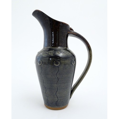 93 - A studio pottery jug by Jennie Gilbert with banded fish detail to shoulder and relief roundel decora... 