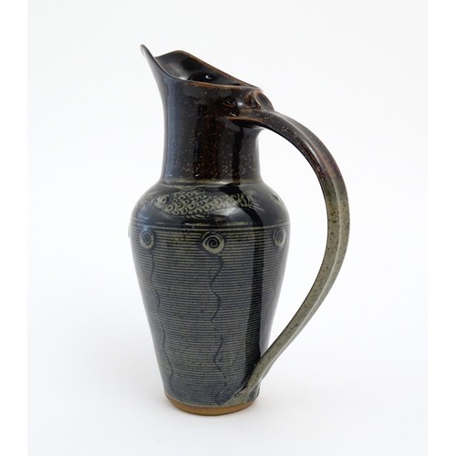 93 - A studio pottery jug by Jennie Gilbert with banded fish detail to shoulder and relief roundel decora... 