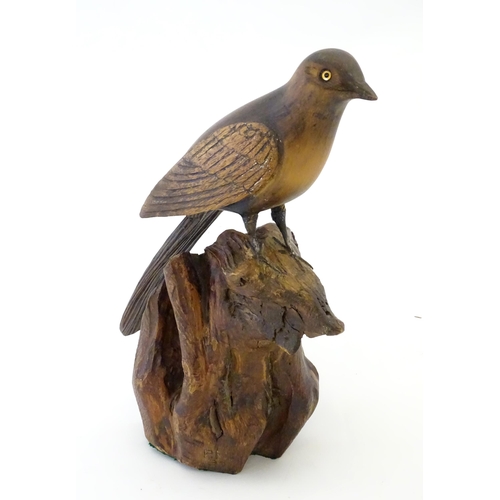 865 - A 20thC carved wooden model of bird on a rocky outcrop. Signed with initials P. N. and dated (19)37 ... 