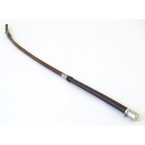 891 - A 19thC riding whip, having woven leather detail with a white metal collar & pommel with C scroll de... 