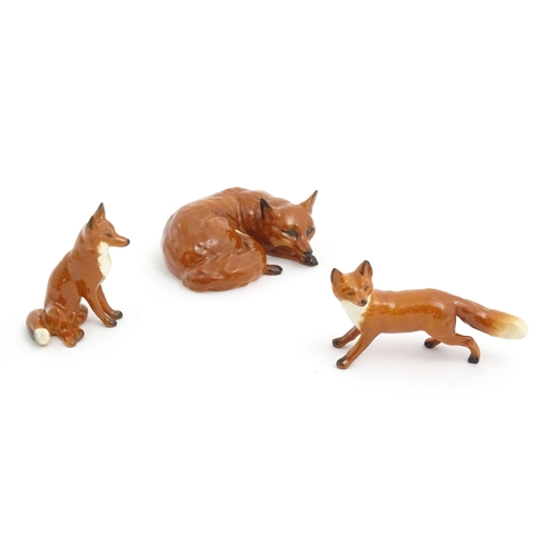 131 - Three Beswick models of foxes, comprising a seated fox, no. 1728, a standing fox, no. 1440, and a cu... 