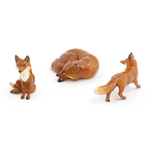 131 - Three Beswick models of foxes, comprising a seated fox, no. 1728, a standing fox, no. 1440, and a cu... 