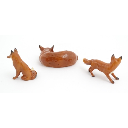 131 - Three Beswick models of foxes, comprising a seated fox, no. 1728, a standing fox, no. 1440, and a cu... 