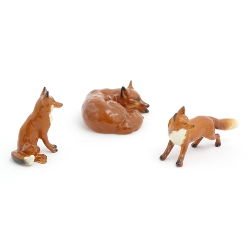 131 - Three Beswick models of foxes, comprising a seated fox, no. 1728, a standing fox, no. 1440, and a cu... 