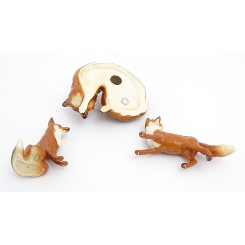 131 - Three Beswick models of foxes, comprising a seated fox, no. 1728, a standing fox, no. 1440, and a cu... 