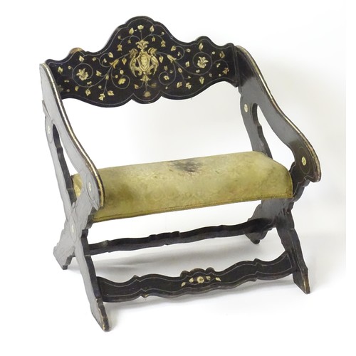 1506 - A late 18thC / early 19thC continental x-frame chair, having an ebonised frame with decorative bone ... 