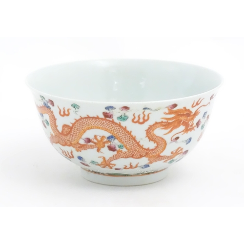 14 - A Chinese famille rose bowl decorated with two dragons and a flaming pearl. Character marks under. A... 