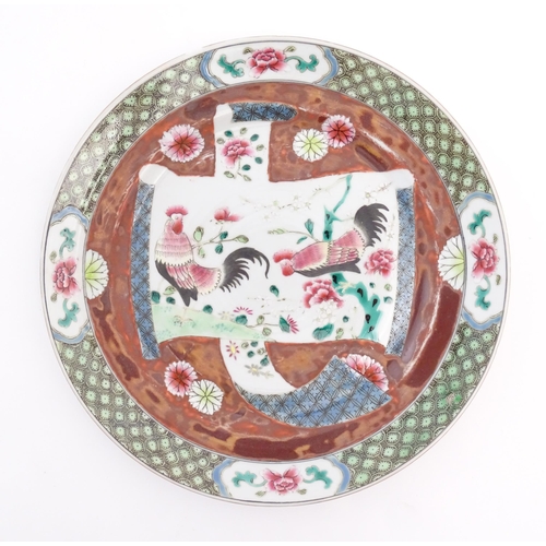 36 - A Chinese plate decorated with a scrolling central panel depicting two cockerels / roosters amongst ... 