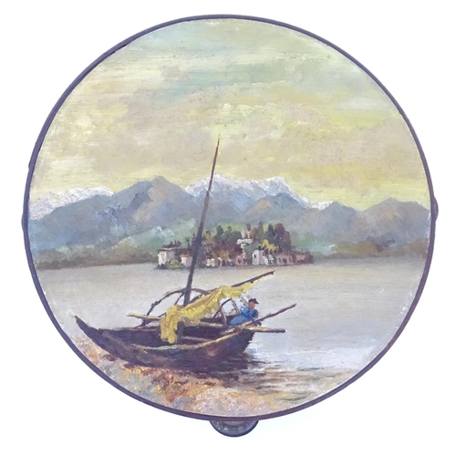 897 - A 20thC tambourine, the drum painted in oils depicting a Continental lake scene with fisherman, boat... 