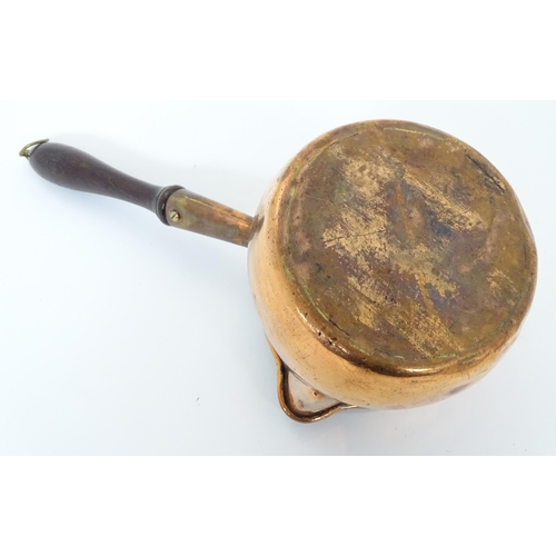 900 - A 19thC copper saucepan with spout and turned wooden handle. Approx. 14 1/4