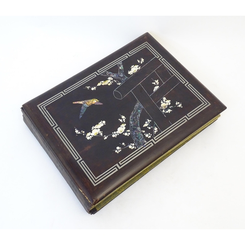 1960 - A Japanese photograph album with lacquered boards, the cover decorated with inlaid mother of pearl a... 