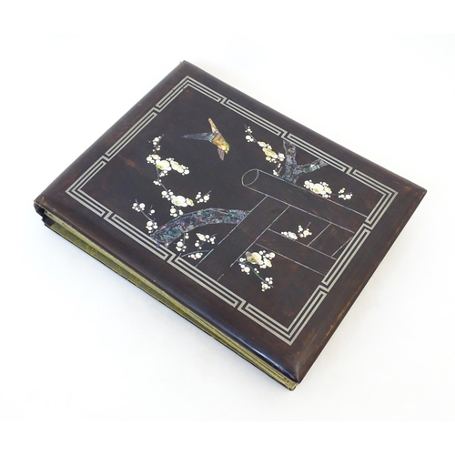 1960 - A Japanese photograph album with lacquered boards, the cover decorated with inlaid mother of pearl a... 