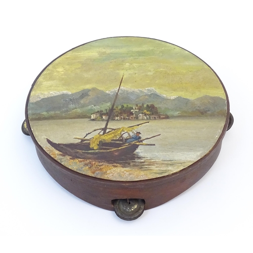 897 - A 20thC tambourine, the drum painted in oils depicting a Continental lake scene with fisherman, boat... 