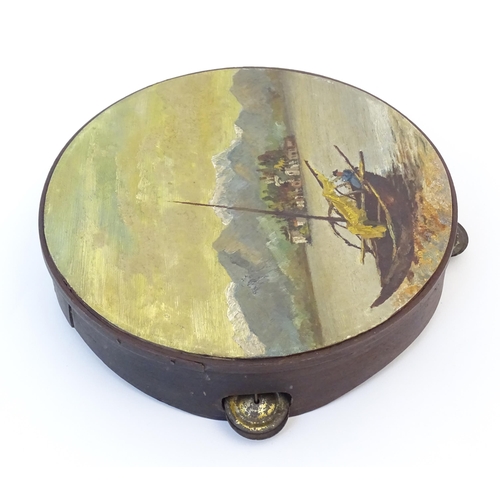 897 - A 20thC tambourine, the drum painted in oils depicting a Continental lake scene with fisherman, boat... 