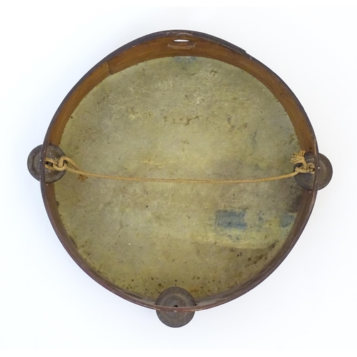 897 - A 20thC tambourine, the drum painted in oils depicting a Continental lake scene with fisherman, boat... 