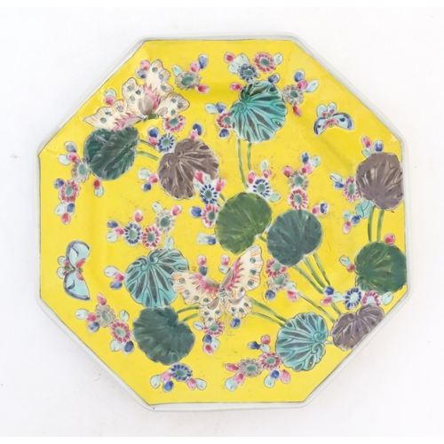 45 - A Chinese octagonal plate with a yellow ground decorated with butterflies, flowers and foliage. Appr... 