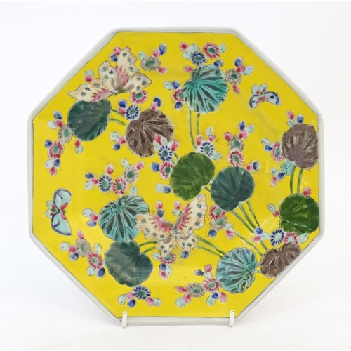 45 - A Chinese octagonal plate with a yellow ground decorated with butterflies, flowers and foliage. Appr... 