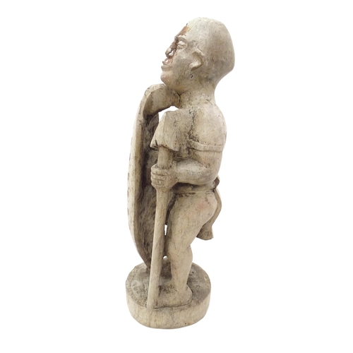 893 - Ethnographic / Native / Tribal: An African carved wood figure with a shield and spear. Approx. 17