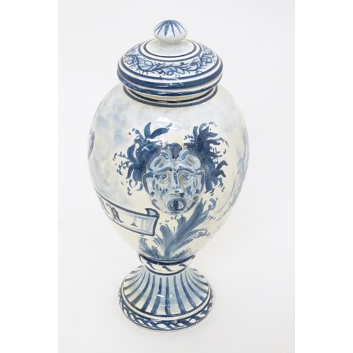 11 - A Continental blue and white faience style pedestal vase and cover with twin mask handles, the body ... 
