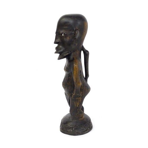 45 - Ethnographic / Native / Tribal: An African carved hardwood figure with inlaid eyes and carved decora... 