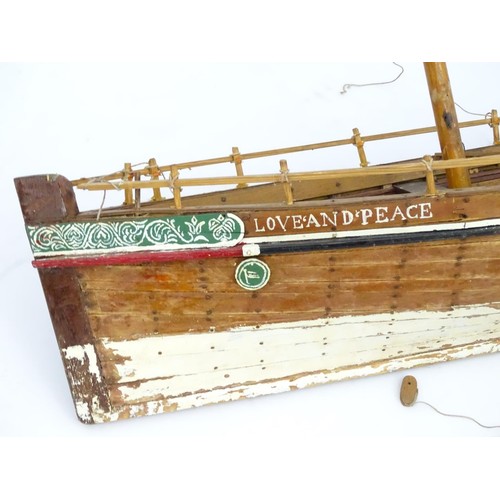 69 - A model of a sail boat, the hull titled Love and Peace. Approx 48