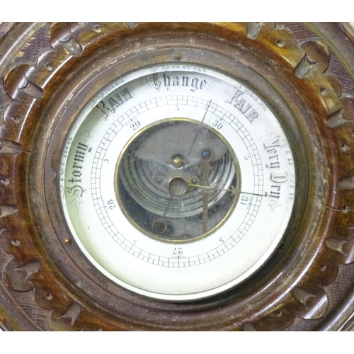 71 - An aneroid barometer / thermometer within a carved wooden surround. Approx 16