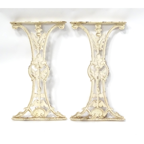 48 - A pair of cast and white painted table support with floral and thistle detail, bearing marks for H. ... 
