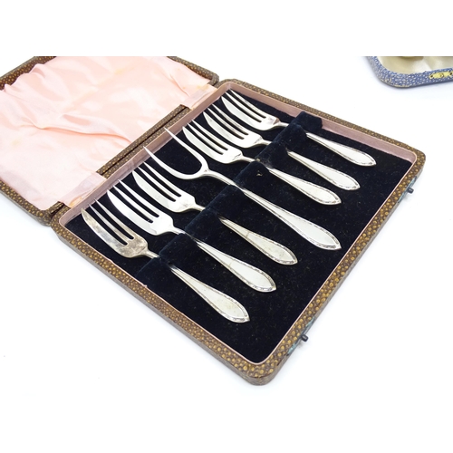 951 - A cased set of silver plate cake forks and served together with a cased set of six silver plated spo... 