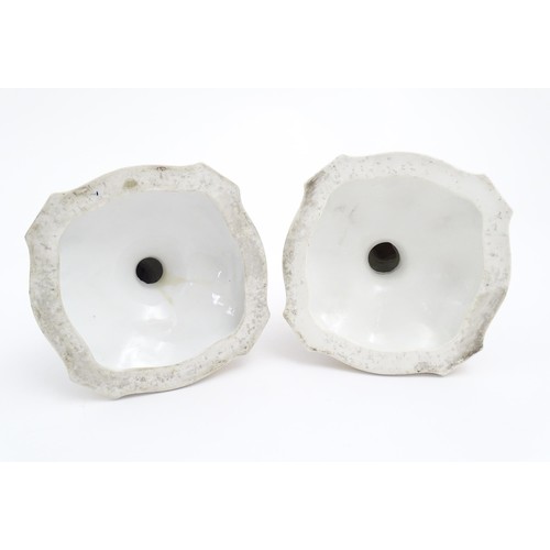 96A - A pair of Continental porcelain figural candlesticks on shaped bases with scrolling floral and folia... 