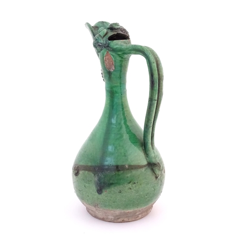 88 - A Turkish Canakkale pottery jug / ewer with a green glaze. Approx. 14