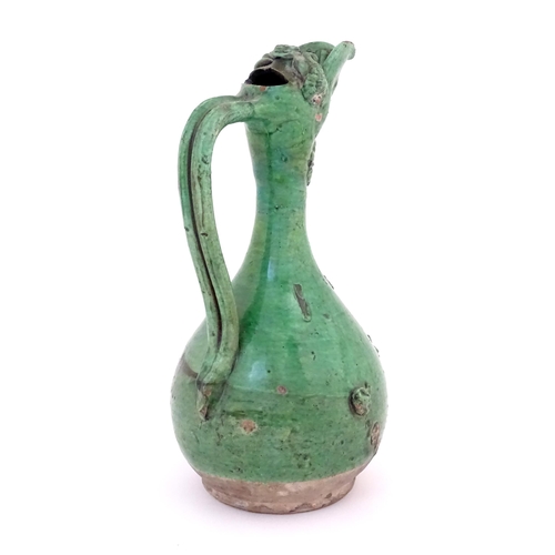 88 - A Turkish Canakkale pottery jug / ewer with a green glaze. Approx. 14