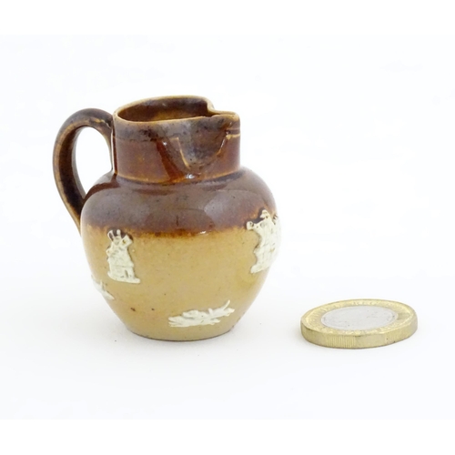 102 - A miniature Doulton Lambeth two tone stoneware jug with relief hunting decoration. Marked under. App... 