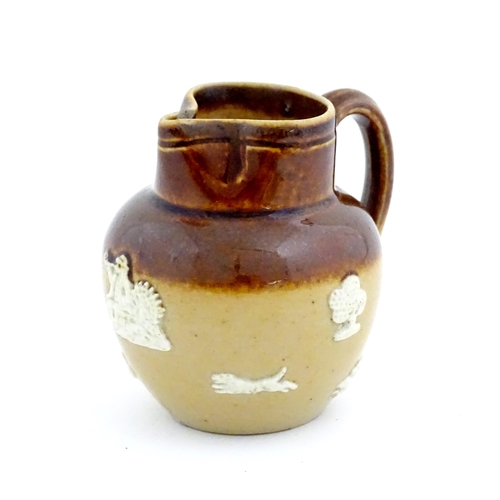 102 - A miniature Doulton Lambeth two tone stoneware jug with relief hunting decoration. Marked under. App... 