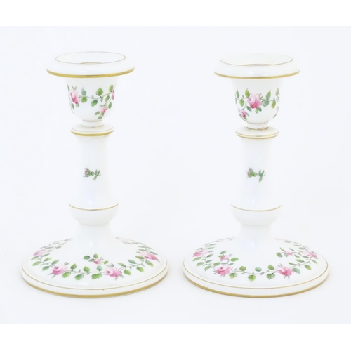 104 - A pair of Royal Worcester candlesticks with banded rose and foliate detail and gilt highlights. Mark... 