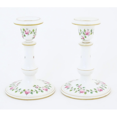 104 - A pair of Royal Worcester candlesticks with banded rose and foliate detail and gilt highlights. Mark... 