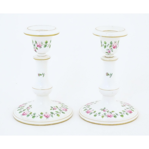 104 - A pair of Royal Worcester candlesticks with banded rose and foliate detail and gilt highlights. Mark... 