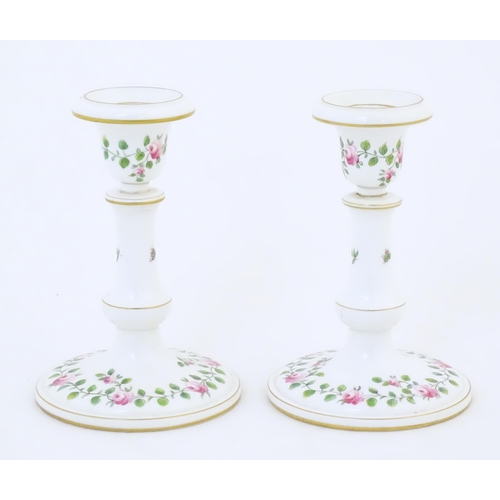 104 - A pair of Royal Worcester candlesticks with banded rose and foliate detail and gilt highlights. Mark... 