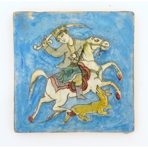 122 - A Persian / Middle Eastern tile with hand painted decoration depicting a man with a sword on horseba... 