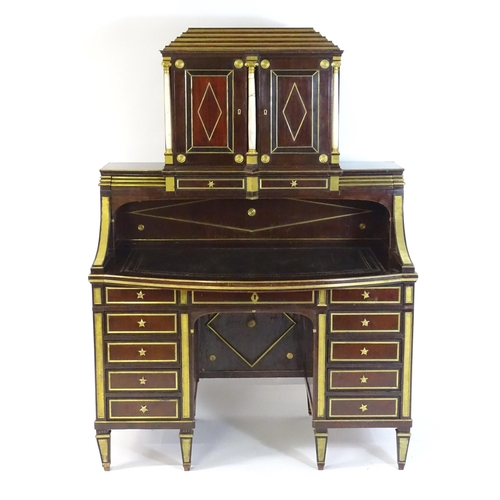 An early 19thC Russian mahogany, brass and giltwood desk, The upmost section having a stepped top above two doors with lozenge decoration and three ionic columns. Having two concealed sprung drawers below the cupboard, the desk having an inset leather top above a single long drawer and two banks of four short drawers, the desk raised on tapering neo - classical style feet. Within the kneehole desk there are nine concealed secret drawers. 49" wide x 27" deep x 68" high.
