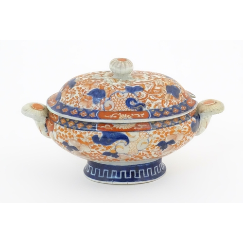 67A - A sauce tureen and cover with twin handles decorated in the Imari palette with scrolling flowers and... 