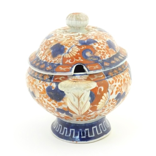 67A - A sauce tureen and cover with twin handles decorated in the Imari palette with scrolling flowers and... 