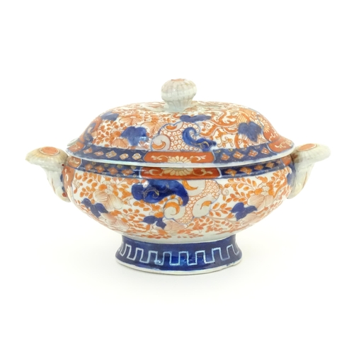 67A - A sauce tureen and cover with twin handles decorated in the Imari palette with scrolling flowers and... 