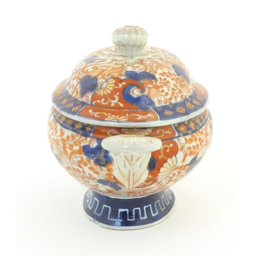 67A - A sauce tureen and cover with twin handles decorated in the Imari palette with scrolling flowers and... 