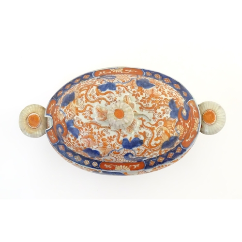 67A - A sauce tureen and cover with twin handles decorated in the Imari palette with scrolling flowers and... 