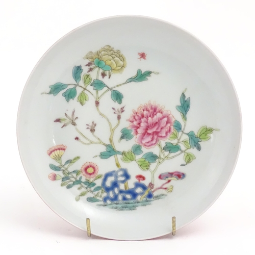 13 - A small Chinese famille rose plate decorated with a stylised rocky outcrop with flowers and foliage.... 