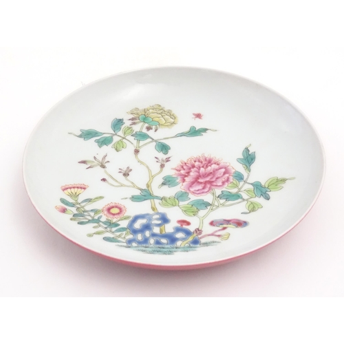 13 - A small Chinese famille rose plate decorated with a stylised rocky outcrop with flowers and foliage.... 