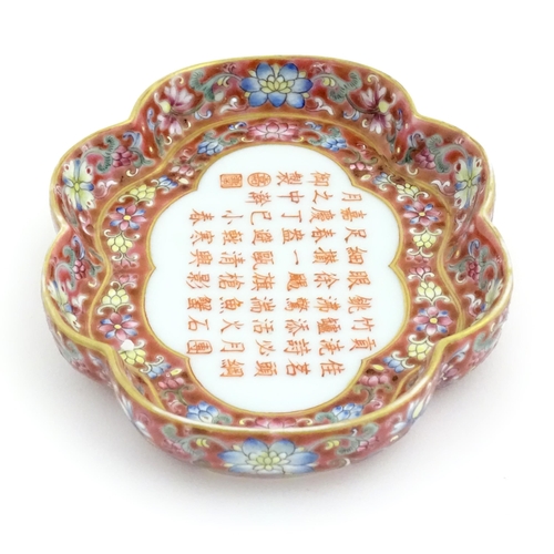 32 - A Chinese dish of shaped form with a pink ground decorated with Character script bordered by flowers... 