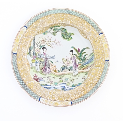 14 - A Chinese / Cantonese plate decorated with a garden scene with two ladies holding fans, with butterf... 