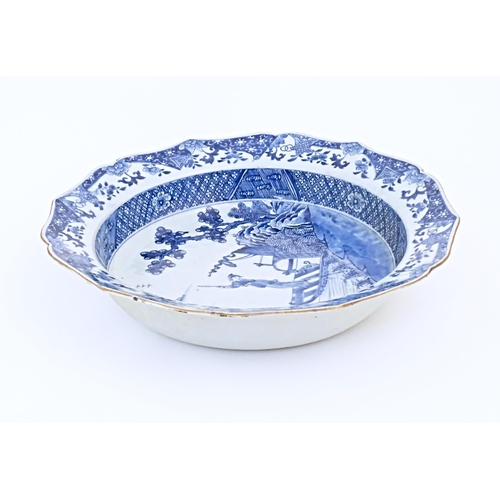 7 - A Chinese blue and white bowl with shaped rim, decorated with a coastal scene with a figure and a st... 